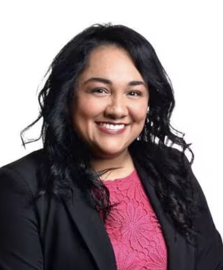 Dark-haired woman smiling wearing bright pink shirt with dark blazer